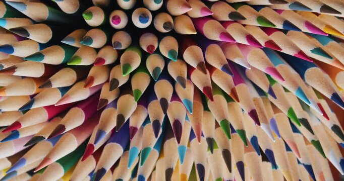 Slow motion macro: group of sharpened multicolored pencils rotate in a circle. Beautiful pencil cores and wooden texture, creative art supplies visual 4K.