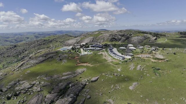 Drone lowers in ultra wide shot on southwest side of mountain resort on a sunny day at Sibebe Rock near Mbabane, Eswatini