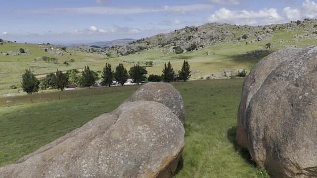 Drone flies behind large boulders while filming two hikers on a sunny day at Sibebe Rock near Mbabane, Eswatini