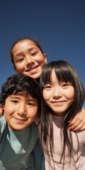 Obraz premium Three children smiling and embracing under clear sky