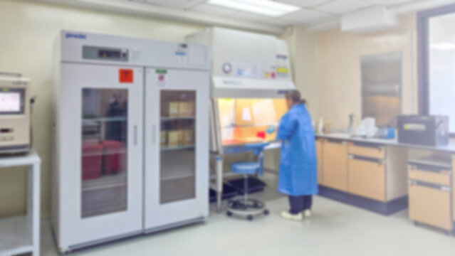 Blur background Laboratory technician working in biosafety cabinet inside lab, sterile technique, scientific equipment, refrigerators, controlled environment for microbiology and medical research.
