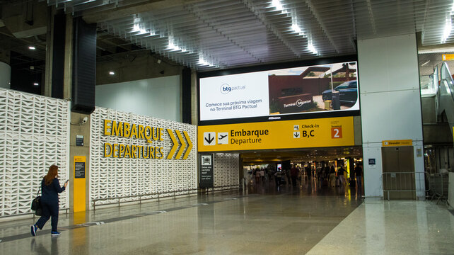 Placa de embarque e departures no Aeroporto Internacional de Guarulhos com passageiros ao redor e sinaliza&ccedil;&atilde;o de dire&ccedil;&atilde;o para voos. Guarulhos SP 10 Abril de 2026