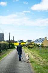 Fototapeta premium Homme seul de dos promenant un labrador sur une petite route du Finistère en France