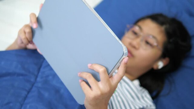 Close-up of young girl's hands holding a digital tablet with blurred face in background for online learning and mobile technology concept