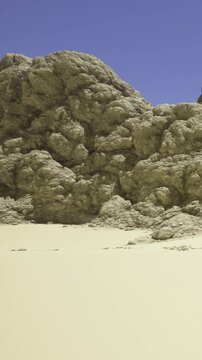 Stunning rock formations rise majestically against a cloudless sky. Warm sunlight casts shadows on the textured surface, revealing natures artistry in this serene desert landscape.