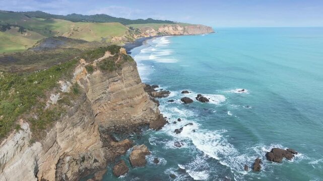 Rugged cliffs and black sand beaches meet the turquoise ocean at Tunnel Beach, Waikato, New Zealand. This dramatic coastline offers stunning views.