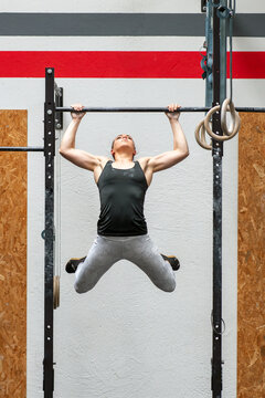 Female athlete performing kipping pull up exercise in gym