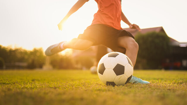 Action sport outdoors of kids having fun playing soccer football for exercise under the twilight sunset sky. Picture with copy space.