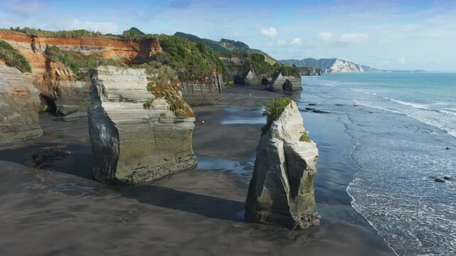 The stunning geological formations of the Three Sisters at Tongaporutu Beach, Taranaki, New Zealand, are sculpted by the Tasman Sea. Coastal landscape showcases layered cliffs and sea stacks