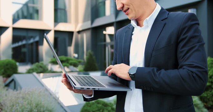Close-up of businessman typing on a laptop outdoors, representing remote work, digital communication and modern technology.
