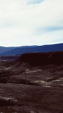 Majestic mountains rise against a clear sky, revealing a serene yet rugged terrain. Soft light casts shadows on the rocky ground, creating a peaceful atmosphere.