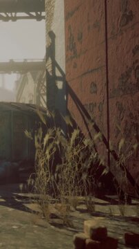 Sunlight filters through the ruins of an abandoned structure, illuminating wild grasses reclaiming their ground amidst rusted metal and crumbling walls, creating a scene of haunting beauty.