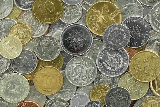 Pile of global currencies, various coin types visible up close. Different nations money together