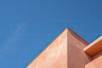 Abstract geometry of a peach-colored building against a bright sky