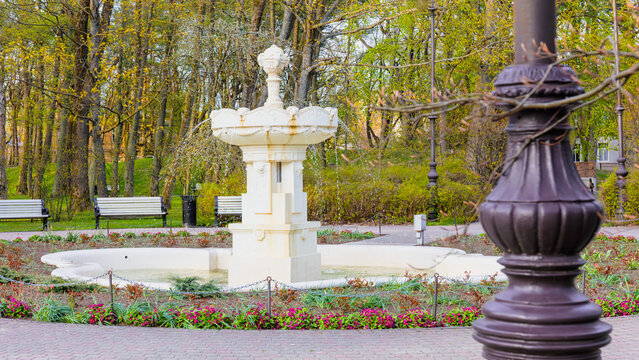 Waiting for warm season surrounds old fountain in liepaja park, where early spring quiet and empty space reflect seasonal pause and local atmosphere, for urban calm and seasonal transition