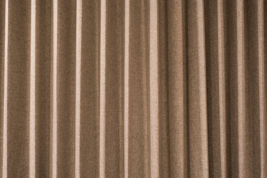 Brown curtain with many folds, background texture. Brown curtain hanging, perfect for decorating a luxurious room or setting