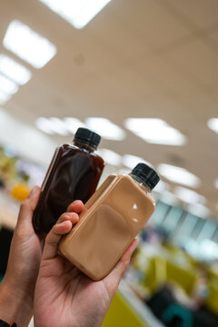 A hand holding a black coffee and mocha bottle in office
