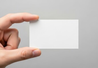 Obraz premium A human hand holding a blank white business card against a neutral grey background mockup