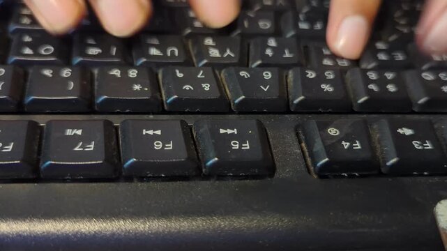 Hands typing on old dusty black computer keyboard close up shot of fingers pressing buttons for data entry work office environment routine programming concept workspace technology daily tasking.