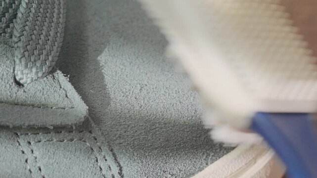 Sneaker cleaning process. Detailed suede sneaker cleaning in home setting. Closeup of soft suede sneaker being carefully cleaned and restored