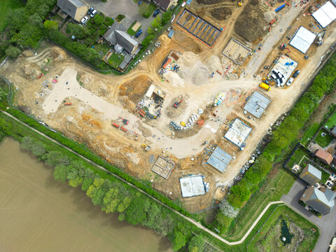 Drone UAV view of  a new housing development site in rural Britain. The foundations of the houses can be seen and the outline of the new road. Seen adjacent to existing houses.