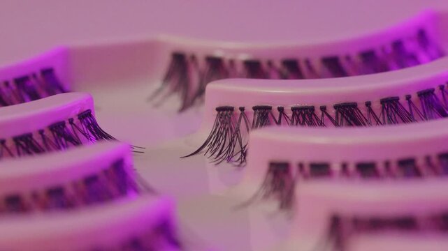 Lash display scene. Eyelash trays under vibrant neon illumination. Luxurious lash presentation using colorful ambient lighting effects
