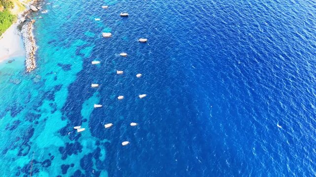Vibrant boats float peacefully in crystal clear waters near a lush coastal landscape under the midday sun