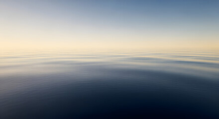 Obraz premium Calm blue ocean water surface under soft sunrise sky at horizon