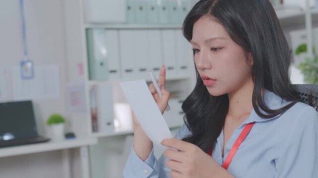 A beautiful Asian woman calculates financial expenses, credit, budget, credit cost, writes receipts and uses a calculator. pays bills, conducts economic market research, tax planning and assessment.
