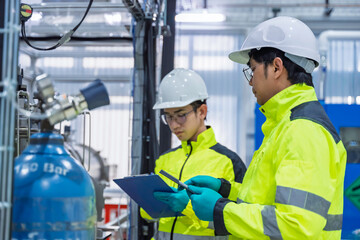 Professional engineers inspecting industrial gas control system and high pressure cylinders in...