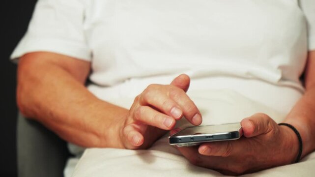A person sits on a couch and holds a smartphone in their hand
