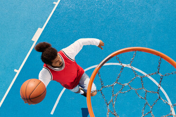 Young man showcases skills on vibrant outdoor basketball court in thrilling game moment © LIGHTFIELD STUDIOS