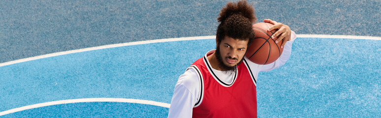 Young man skillfully dribbles basketball on vibrant outdoor court under bright sunlight © LIGHTFIELD STUDIOS
