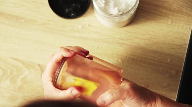 Person holds a clear container with a yellow sponge. The sponge is being pressed down by hands