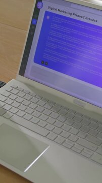 Vertical video: Viewing slide, tapping right arm at desk while in tee and sipping glass near laptop