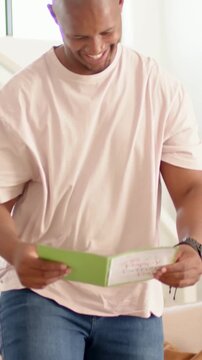 Vertical video: Opening green Fathers Day card dad in pink tee reading placing it on table at home