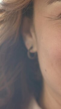 Vertical video: Camera pulling back revealing smiling woman in soft light, with hoop earring