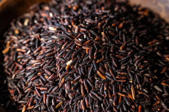 Jasberry, purple rice in a wood bowl on a dark surface 