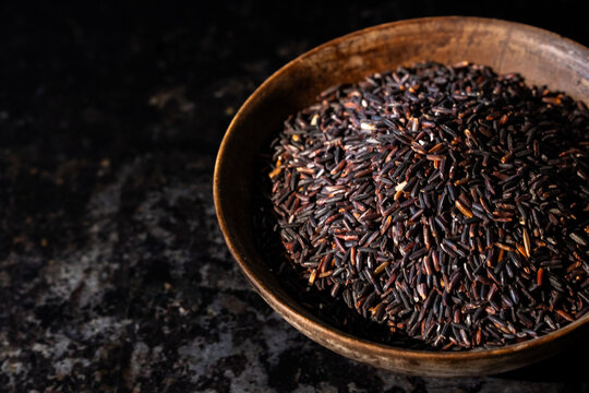 Jasberry, purple rice in a wood bowl on a dark surface 