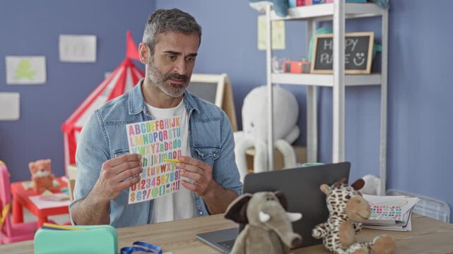 Man holding alphabet sheet and pointing with pencil in classroom building; online teaching concentration.
