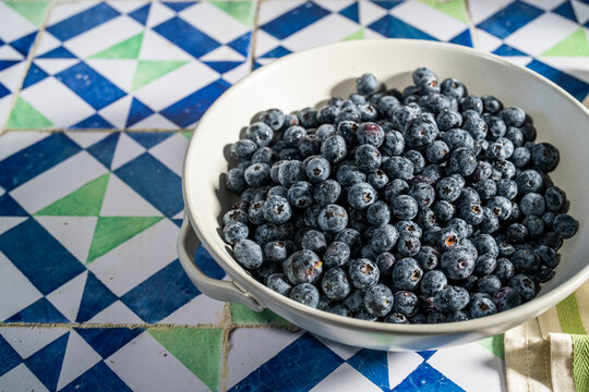 Blueberries in a ceramic colander on a tile countertop 