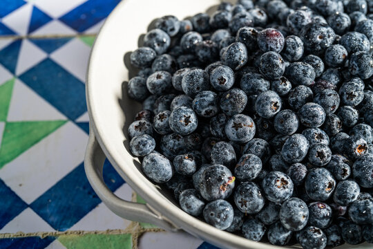 Blueberries in a ceramic colander on a tile countertop 