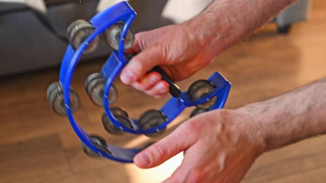 Man Striking Blue Crescent Tambourine Close Up