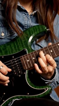 Talented musician playing a close-up of hands on a green quilted maple electric guitar for music tutorials or lifestyle content. Vertical. Video. Portrait Orientation.