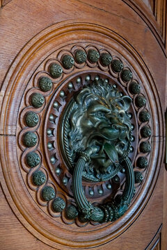 Lion head door knocker on carved oval wood panel