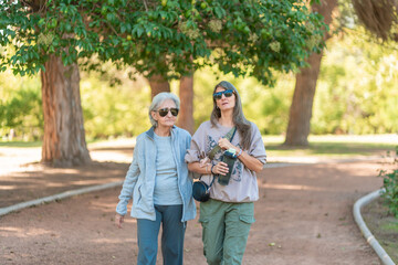 Fototapeta premium An 85 year old grandmother and her daughter enjoy a walk together in a sunny park