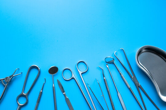 Set of stainless surgical instruments and tools - scalpels, scissors and others - on blue table, top view