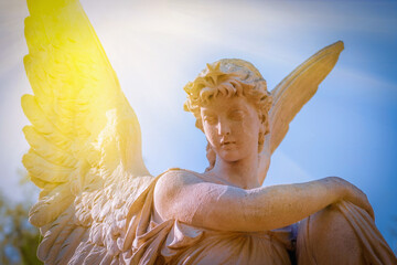 Fototapeta premium Angel statue in warm sunlight, spiritual concept of remembrance, peace and eternity.
