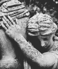 Fototapeta premium Mourning angel statue embracing urn, symbol of grief, loss and remembrance.