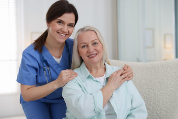Obraz premium Portrait of smiling care worker with senior woman at nursing home